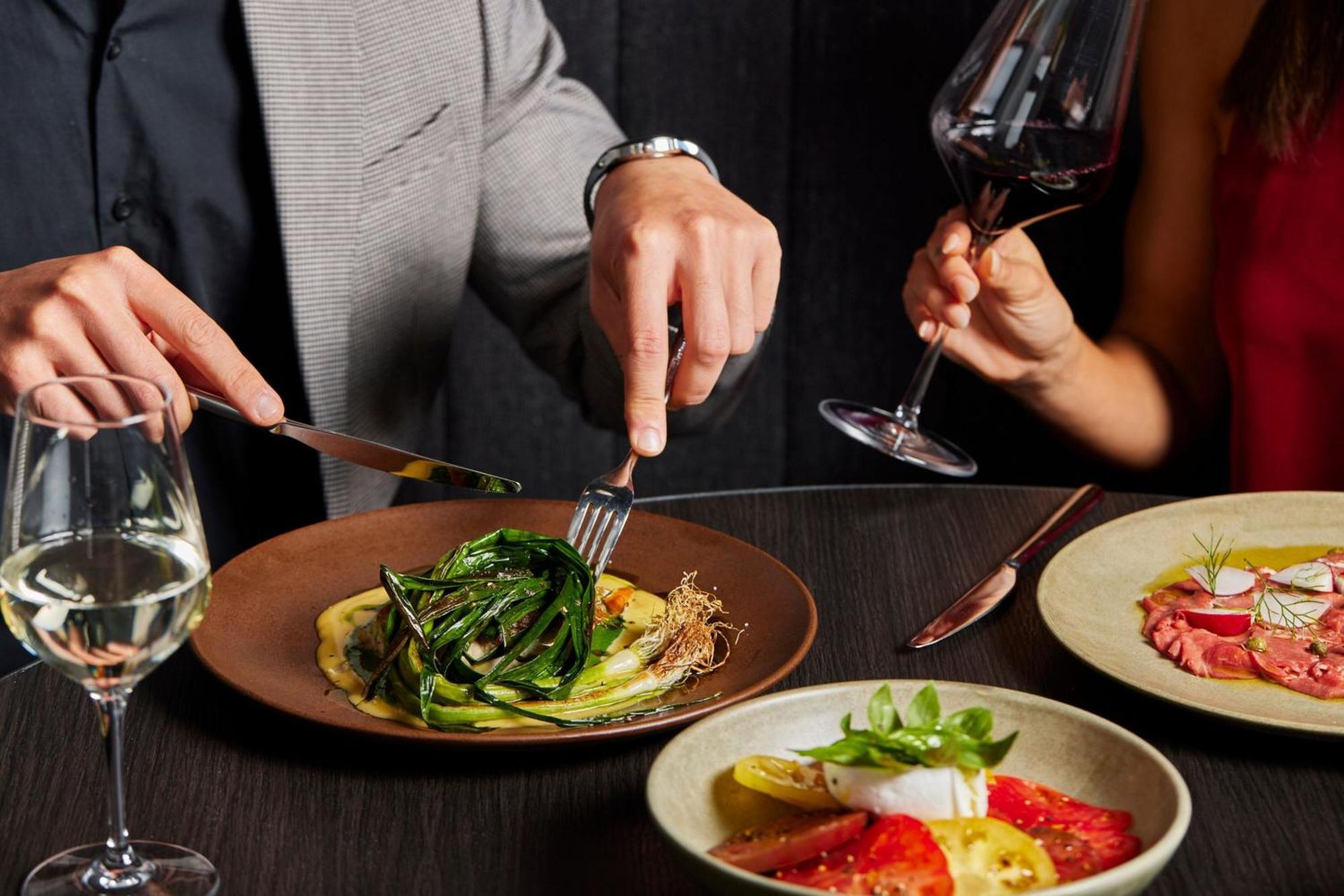 Melbourne Marriott Hotel Docklands Екстер'єр фото A man using a knife and fork to cut into a meal